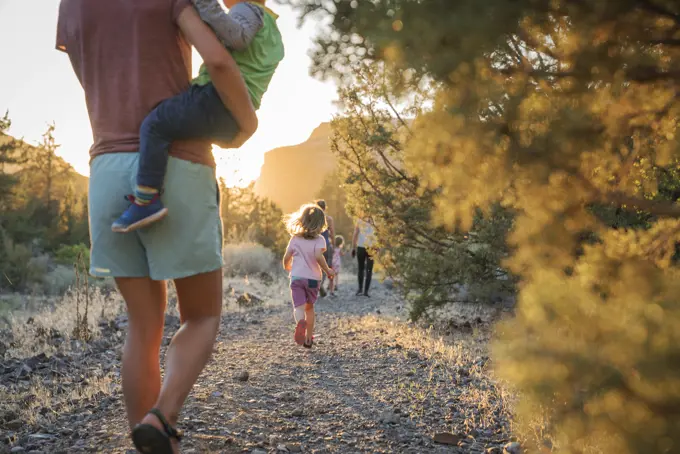 A mom walks with kids down a trail at sunset