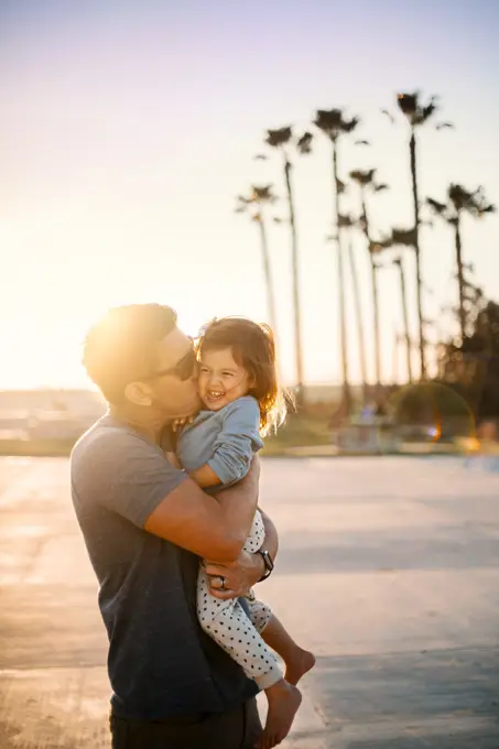 Dad kissing daughter in the sunshine