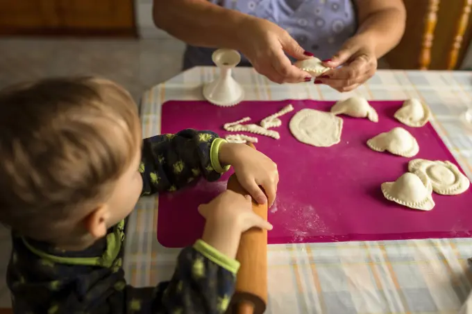 Hands of a woman and child making traditional polish food