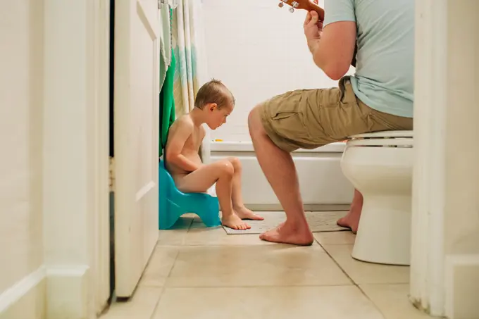 Four year old boy learning to potty train with dad helping