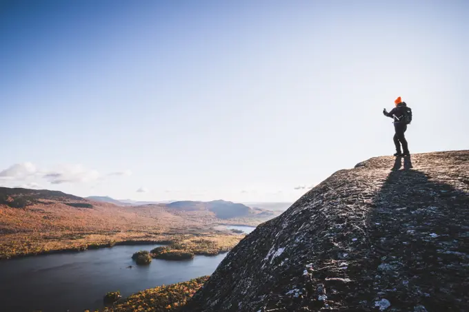 woman hiker takes cell phone picture on mountaintop in Maine in fall