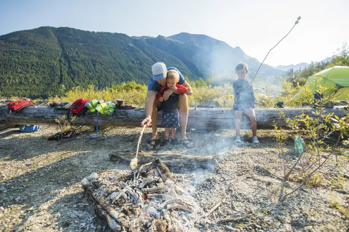 Father and son roast marshmallows over fire during a father son trip