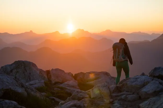 Backpacker hiking on mountain summit, scenic view at sunset