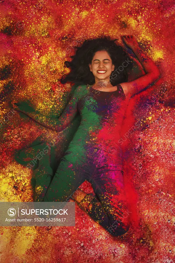 High angle view of a indian teenage girl lying and covered in colored powder during holi color festival