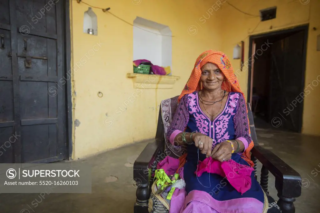 old woman sewing cloth in her house, Rural India