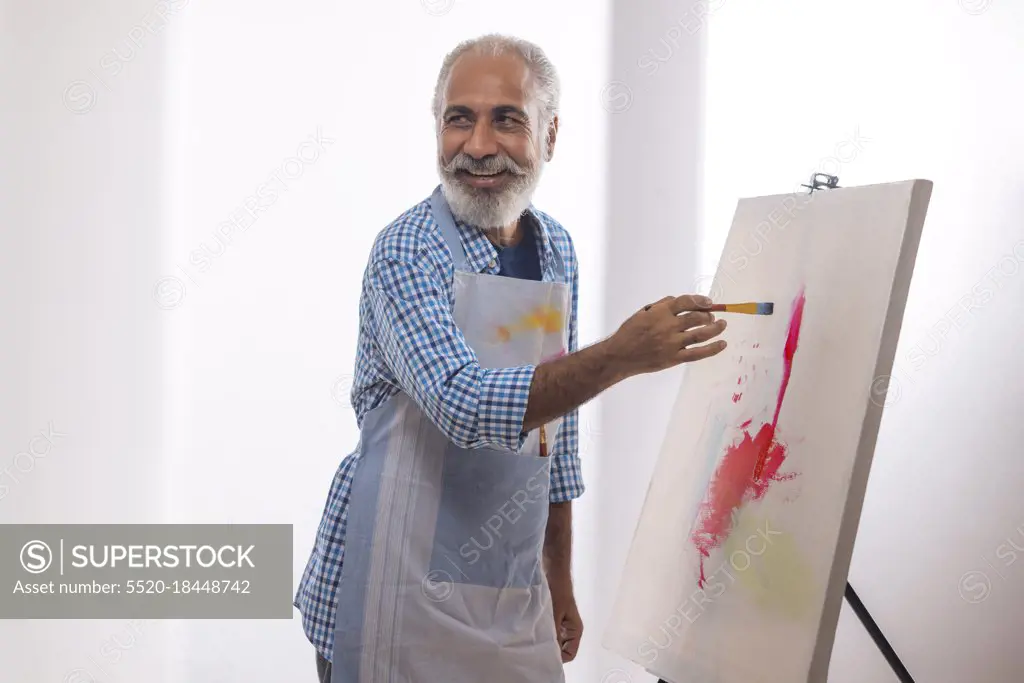 A HAPPY OLD MAN LOOKING AWAY WHILE PAINTING