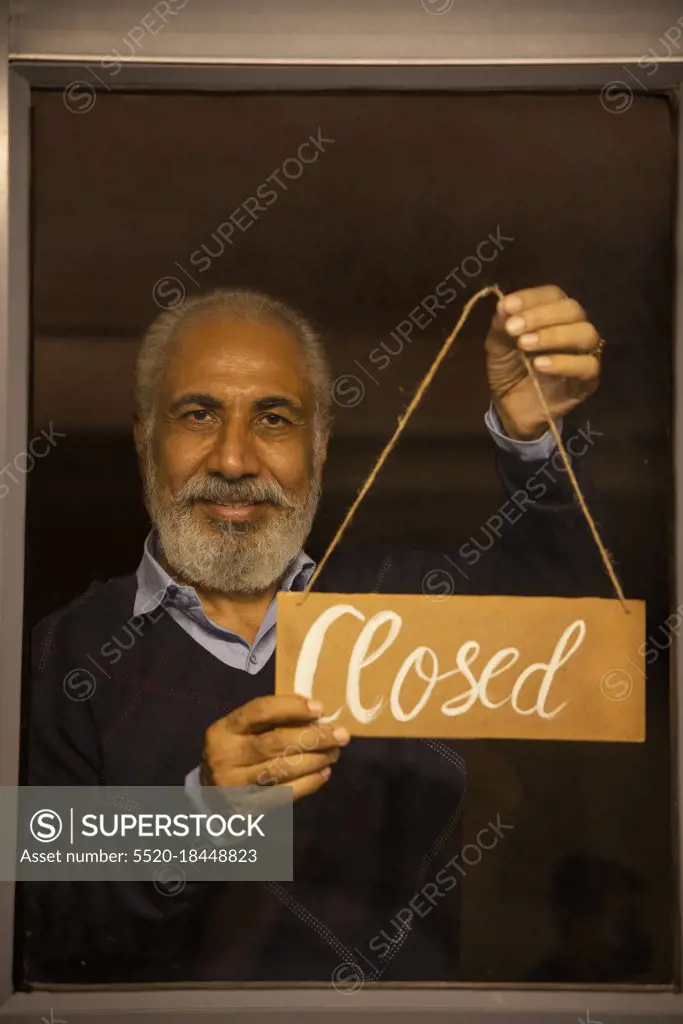 AN OLD MAN HOLDING CLOSED SIGN BOARD