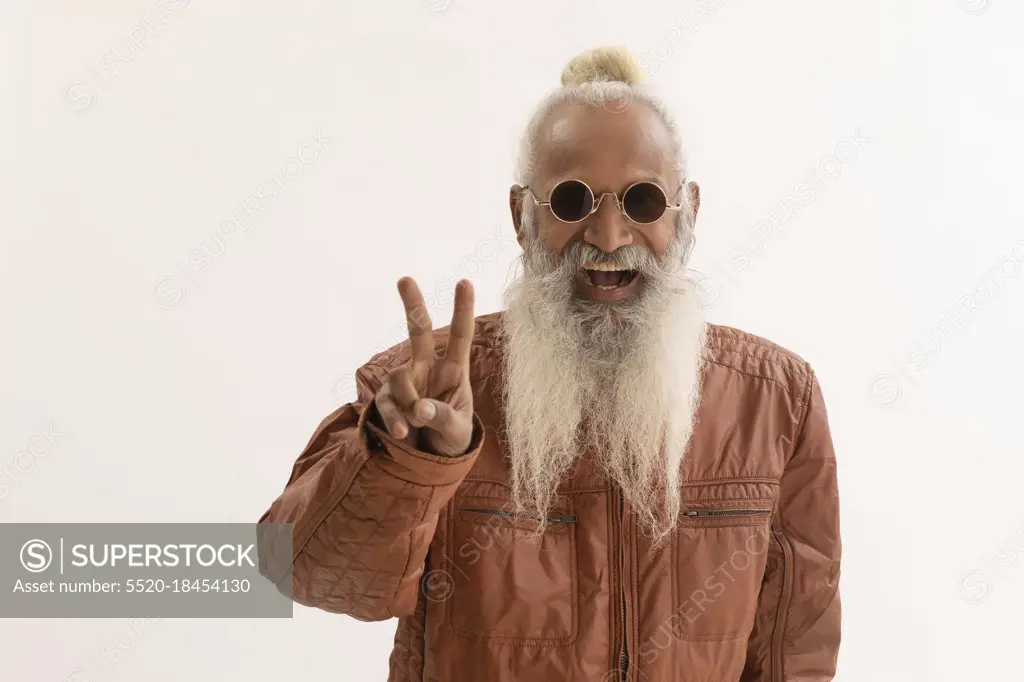 A STYLISH OLD MAN HAPPILY GESTURING AT CAMERA