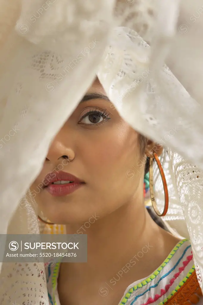 A YOUNG WOMAN LOOKING AT CAMERA FROM WITHIN A WHIITE CLOTH