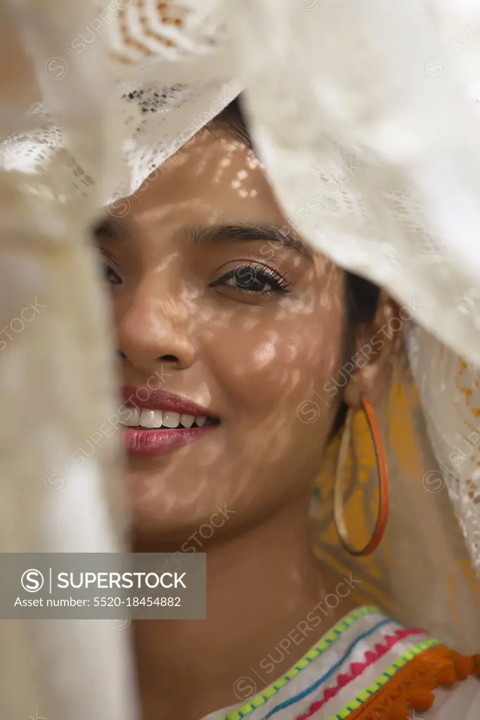 A YOUNG WOMAN HAPPILY POSING FROM WITHIN A WHITE CLOTH