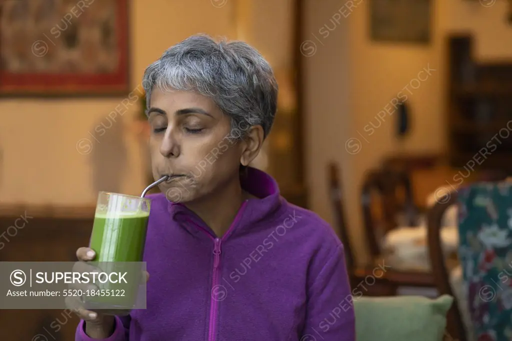 A modern woman sipping fresh green juice using a re-usable metal straw 