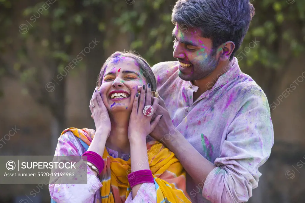 Portrait happy young couple celebrating Holi