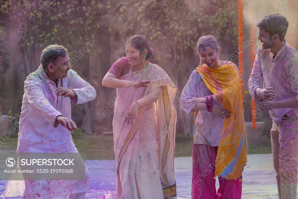 Happy Indian family dancing together on the occasion of Holi
