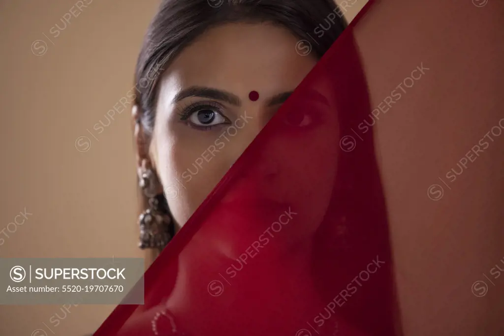 Close-up portrait of young woman with scarf covering face