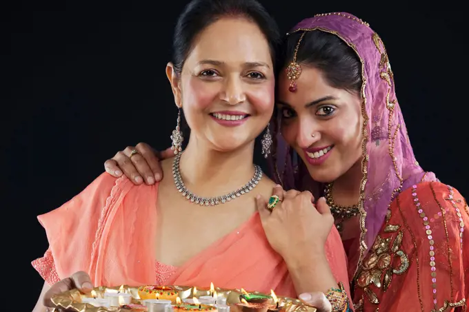 Mother and daughter with a tray of diyas