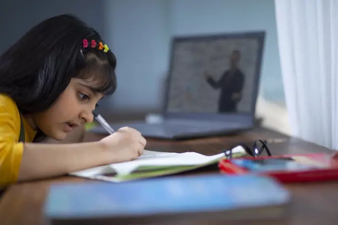 Young girl doing her work while attending virtual class