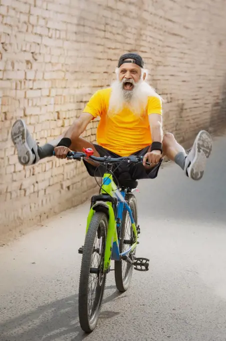 A BEARDED OLD MAN CHEERFULLY POSING WHILE CYCLING