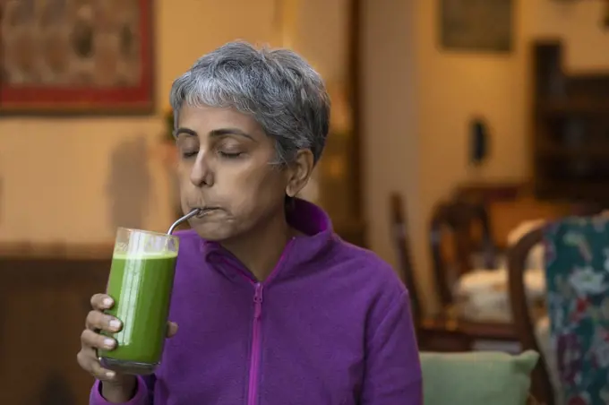 A modern woman sipping fresh green juice using a re-usable metal straw 