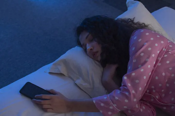 A TEENAGE GIRL SLEEPING WITH PHONE IN HAND