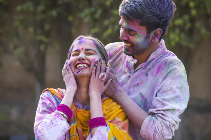 Portrait happy young couple celebrating Holi