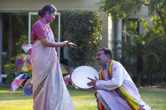 Happy middle aged couple enjoying Holi festival by playing drum