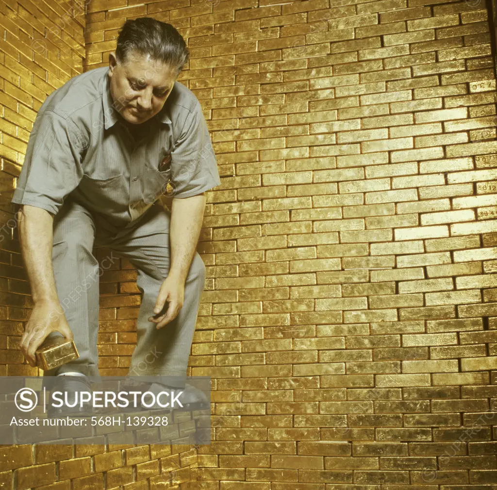 Low angle view of a mature man stacking gold bricks