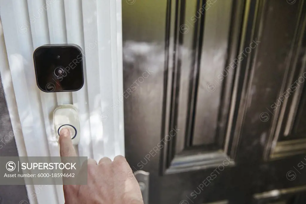 Hand pressing smart home technology video doorbell.