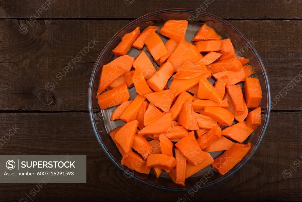 sweet baked pumpkin chopped lomikami in glass dish on wooden background