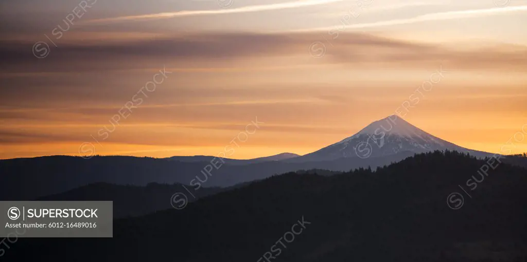 The sun slips down below the horizon and leaves rich saturated orange color around Mt. McLoughlin in the Cascade Range