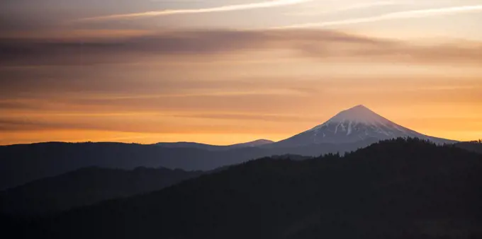 The sun slips down below the horizon and leaves rich saturated orange color around Mt. McLoughlin in the Cascade Range
