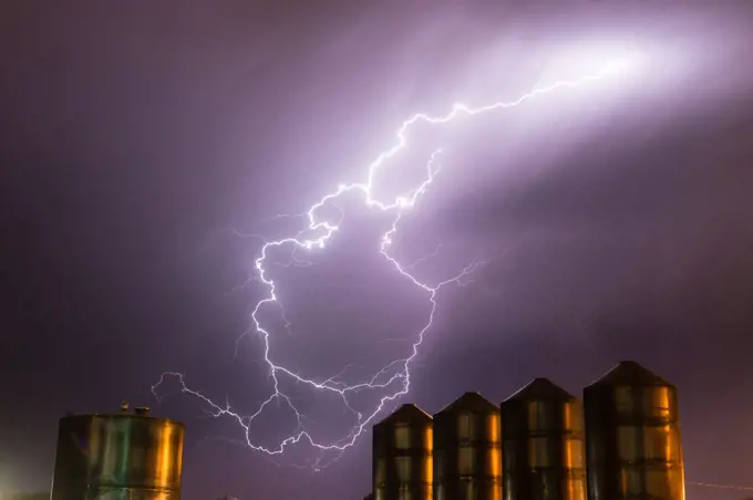 A storm passes over large metal containers releasing electrical charge