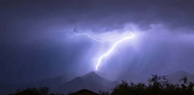 Summer electrical storm produces a lightning bolt illuminating a valley in rural Arizona