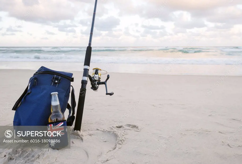 Beer in stubbie holder with Australian Flag, cooler bag and Fishing Rod on  the sand at the beach - SuperStock