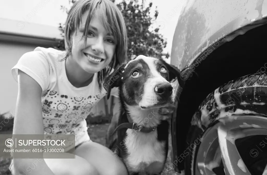 Young woman washing the car and dog together