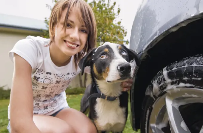 Young woman washing the car and dog together
