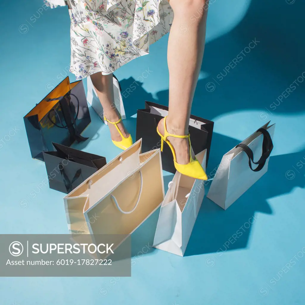 woman leg in fashion shoe over shopping bags, consumer society concept