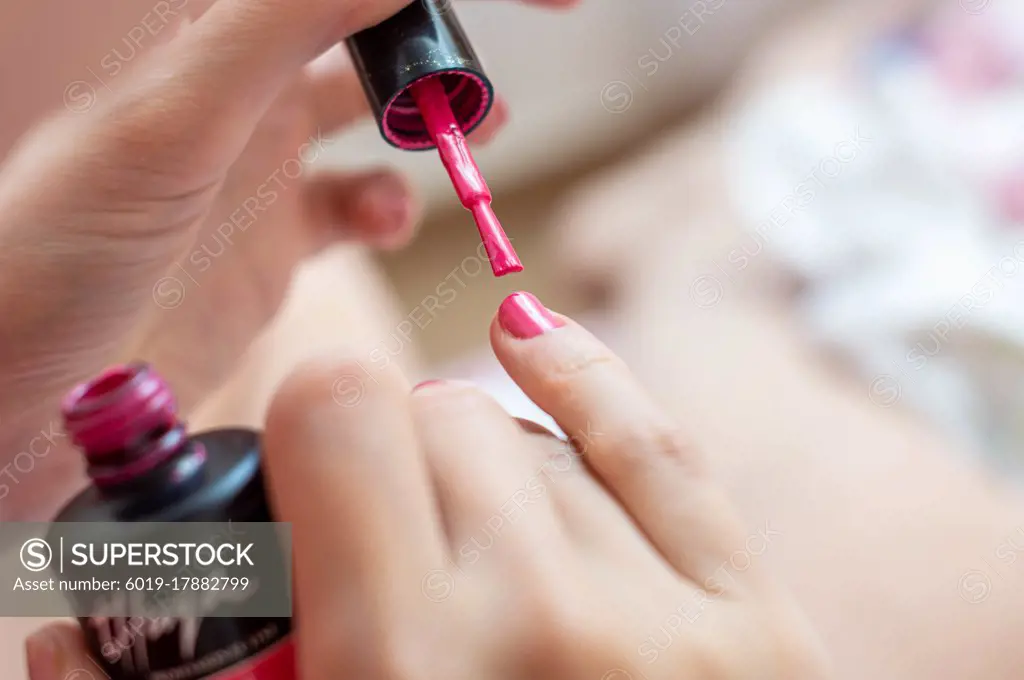 Woman's hands painting nails red