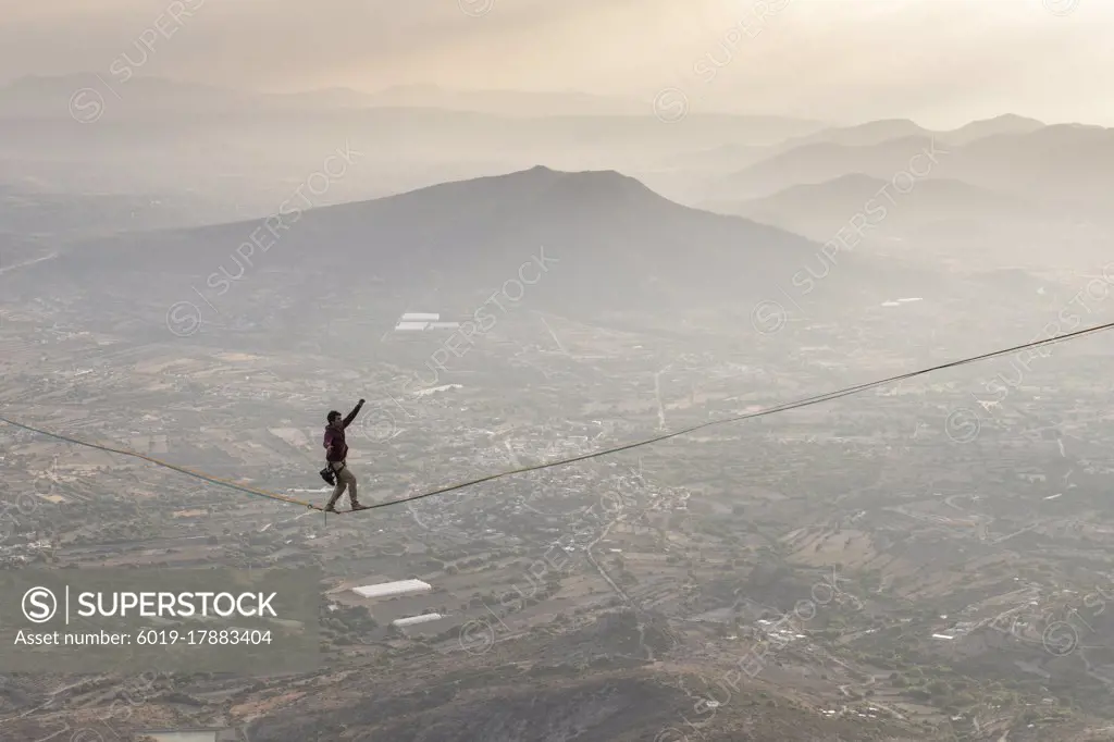 One man balancing on a highline over a valley in a mountain area