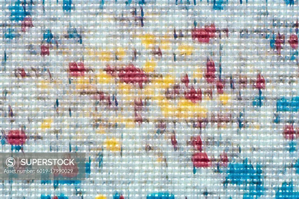 Macro shot of fine white fabric with bright yellow, blue and red blobs