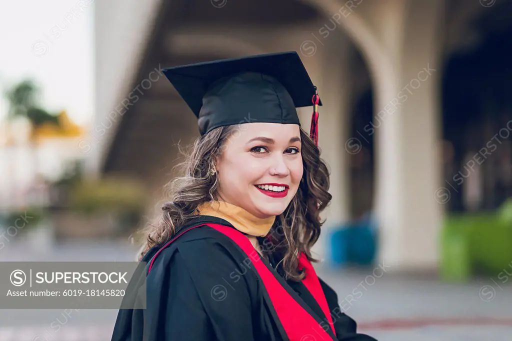 Smiling woman graduating college, wearing a graduation gown/cap.