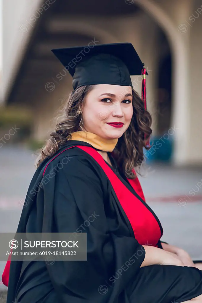 Young woman graduating college, wearing a graduation gown/cap.