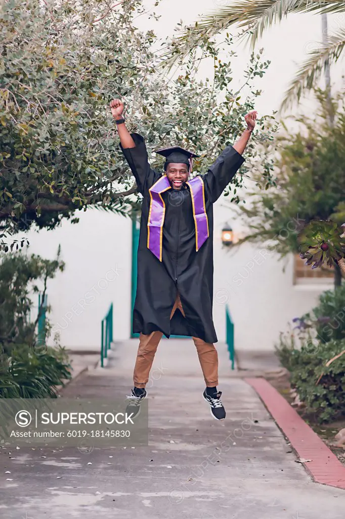 Man excited to be graduating college, wearing a graduation gown/cap.