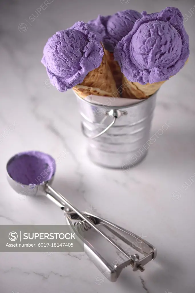 three blueberry ice creams on white marble in metal container