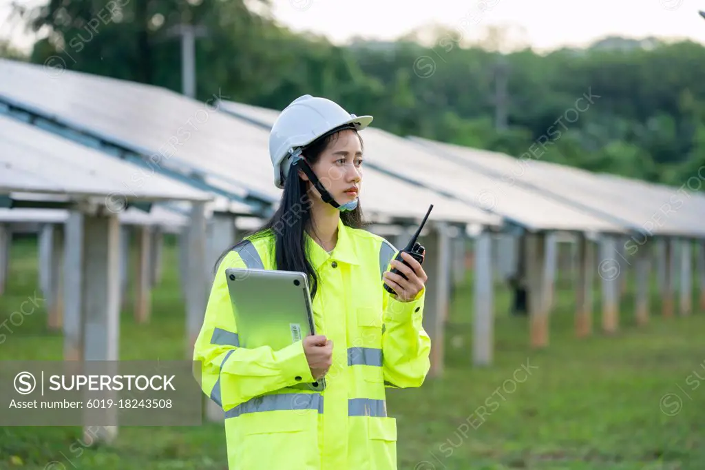 Engineer women wearing safety vest and safety helmet use radio