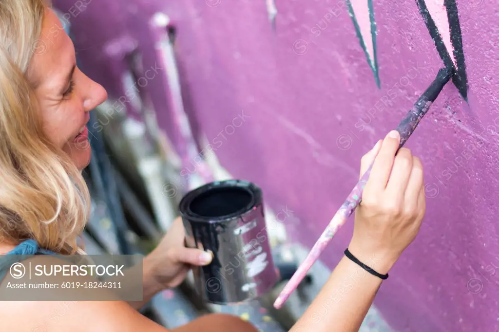 Smiling artist painting wall mural