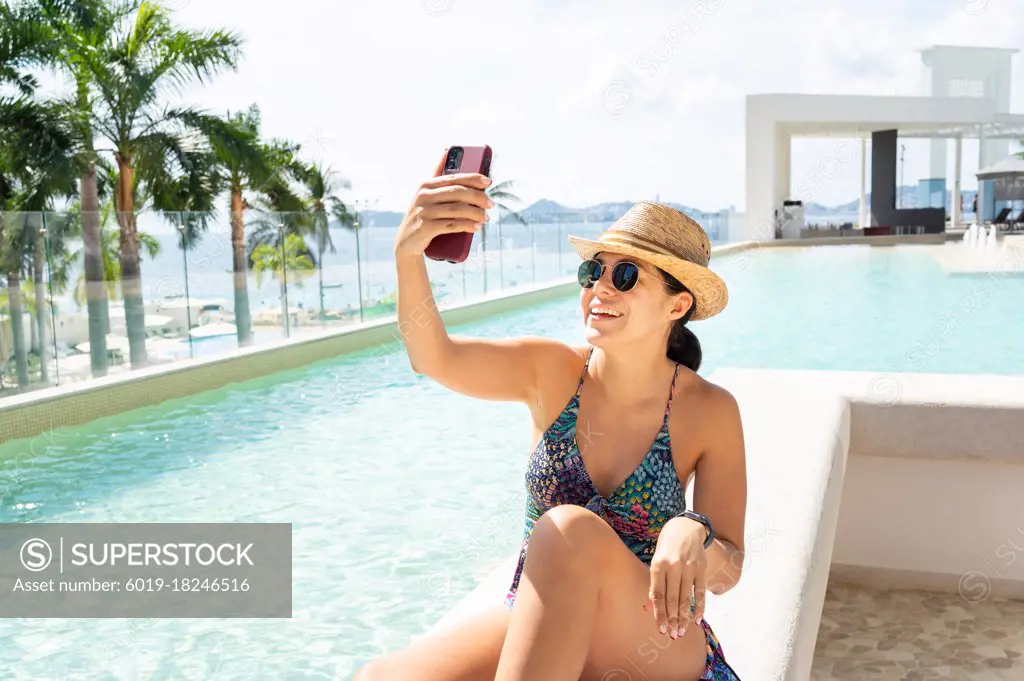 Relaxed happy woman in the pool taking a selfie. Portrait