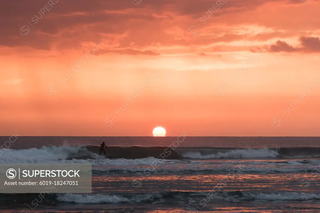 A boy surfing a wave at sunset in cadiz