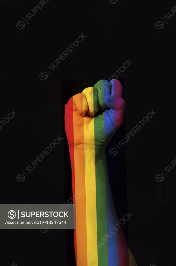 Raised fist colored with the rainbow gay pride on a dark backgro