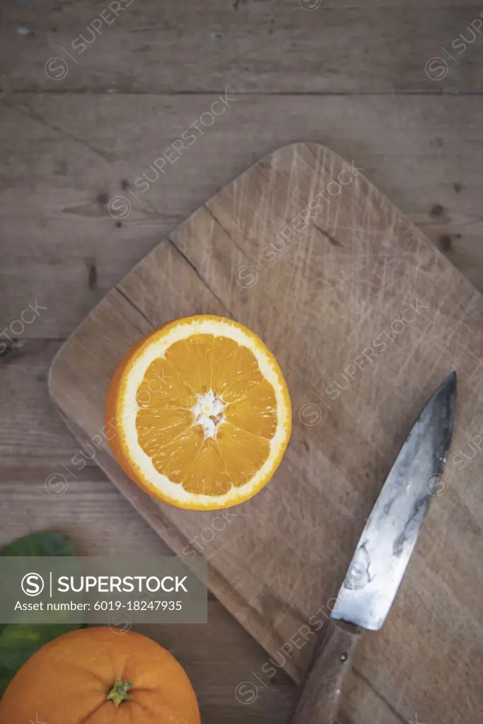 An orange cut on a cutting board with a knife