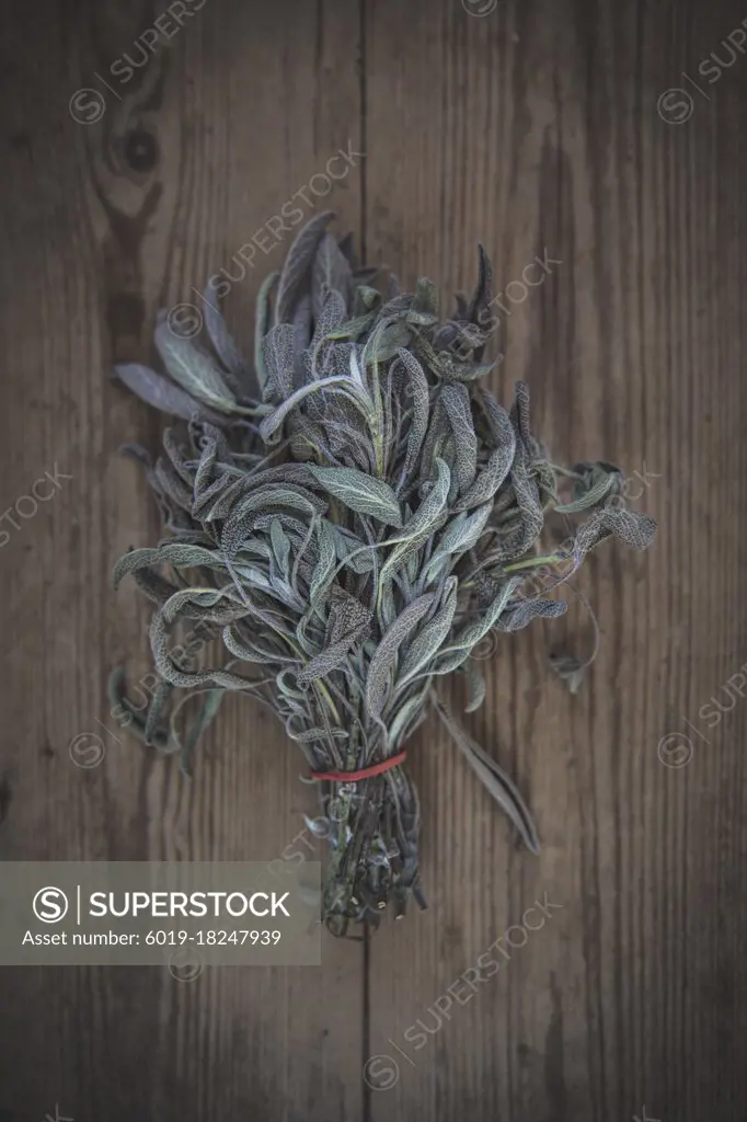 A bundle of sage lies on a wooden table